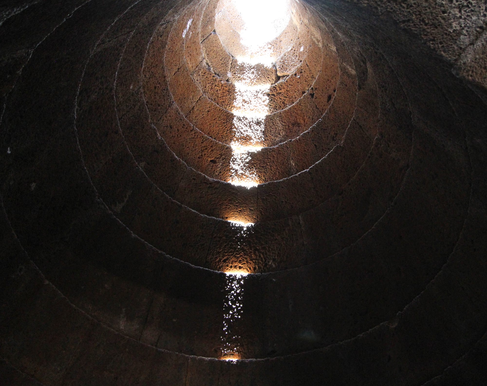 Il foro e la scalinata perfettamente geometrica del pozzo di Santa Cristina
